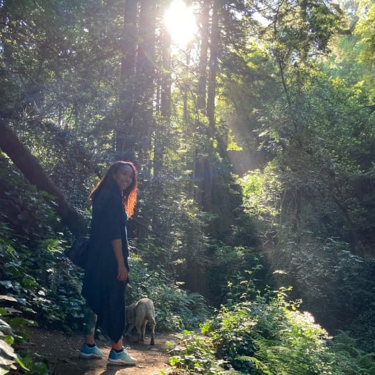 Image of Rebecca hiking in the redwoods with her dog, Snow.